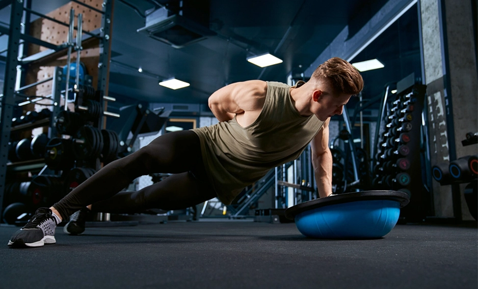 Motivated muscular man doing pushups in a modern gym.